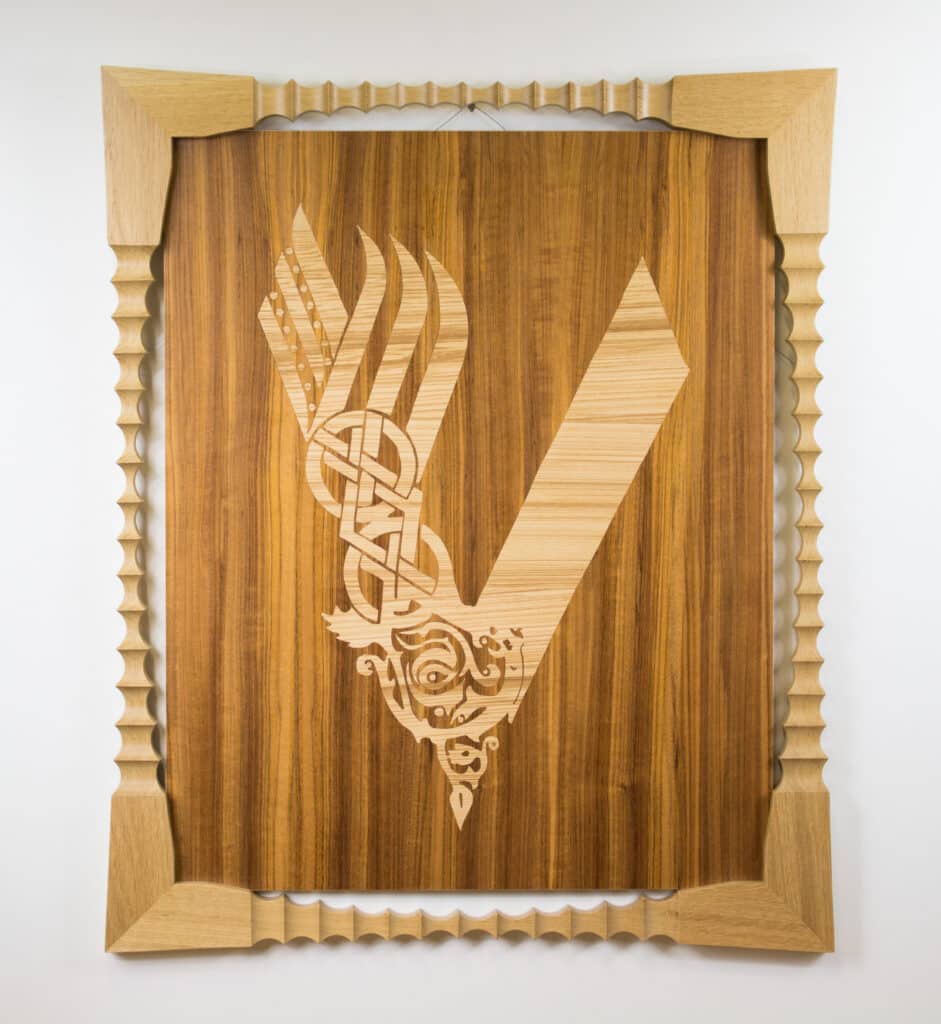 Superbe Art en bois : Logo Vikings en marqueterie sculptée Marqueterie du logo Vikings en bois clair sur fond foncé. Cadre orné et sculpté avec motifs d'inspiration nordique.